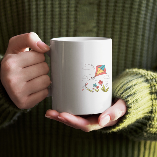 Mug arborant un cerf-volant coloré flottant sous un ciel de printemps radieux
