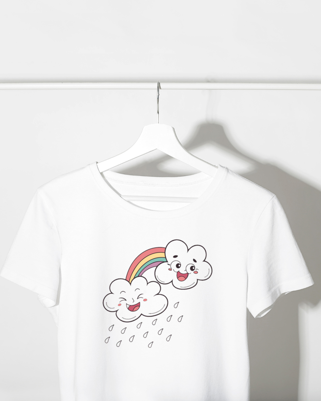 T-shirt fantaisie affichant des nuages souriants et un arc-en-ciel, style doodle