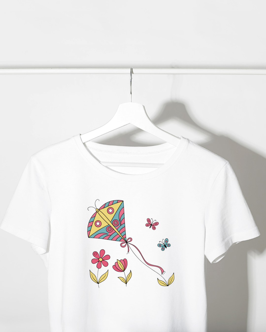 T-shirt vibrant avec cerf-volant joyeux et papillons dans un jardin de fleurs pastel